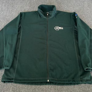 May include: A dark green fleece jacket with a full-length zipper and a high collar. The jacket has long sleeves and a small logo on the chest. The jacket is made of a soft, warm material.