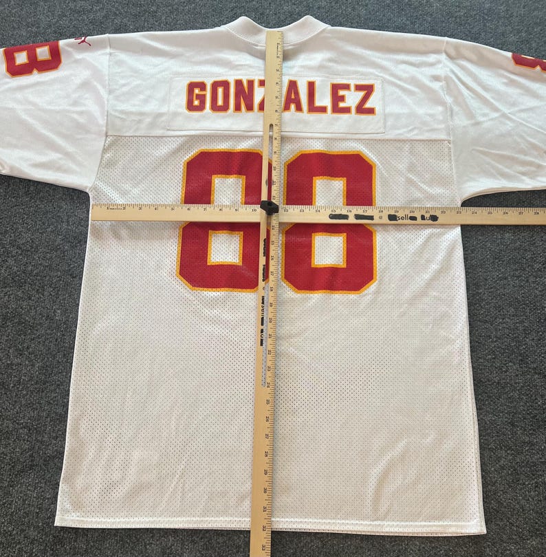 Op de afbeelding: Wit mesh sportshirt met rode en gouden accenten. Het shirt toont de naam "GONZALEZ" op de rug en het nummer "88" op de voor- en achterkant. Het heeft een V-hals en korte mouwen.