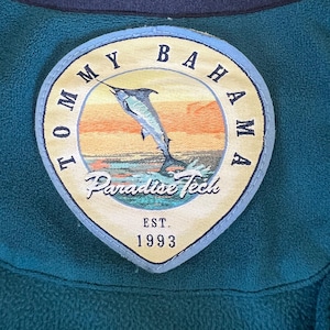 May include: A blue and yellow embroidered patch with the text 'Tommy Bahama Paradise Tech Est. 1993' and a cartoon image of a marlin jumping out of the water.