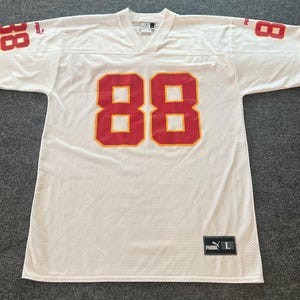 Op de afbeelding: Wit mesh sportshirt met rode en gele accenten. Het nummer 88 staat in het rood op de voorkant en de mouwen. De mouwen hebben gele en rode strepen. Een Puma-logo en maatlabel zijn zichtbaar.