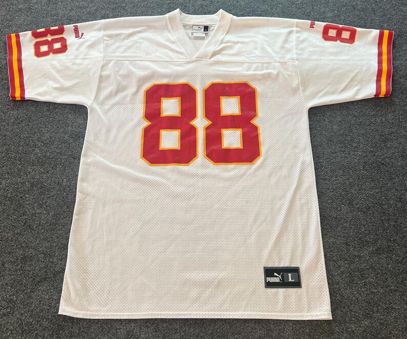 Op de afbeelding: Wit mesh sportshirt met rode en gele accenten. Het nummer 88 staat in het rood op de voorkant en de mouwen. De mouwen hebben gele en rode strepen. Een Puma-logo en maatlabel zijn zichtbaar.
