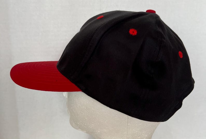 May include: A black and red baseball cap with a red brim. The cap is made of a soft, comfortable fabric.