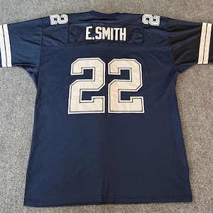 May include: Navy blue football jersey with white accents. The jersey features the number 22 in white on the front and back, with the name "E. SMITH" above the number on the back. White stripes adorn the sleeves.