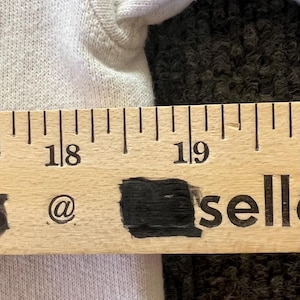 Peut inclure: Un v&ecirc;tement en tissu blanc plac&eacute; derri&egrave;re une r&egrave;gle en bois. La r&egrave;gle affiche les chiffres 18 et 19, avec le texte @ et sell visible sous les chiffres. La r&egrave;gle indique une mesure allant de 45,7 cm &agrave; plus de 48,3 cm.