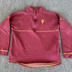 May include: Maroon quarter-zip sweatshirt with gold stitching and a small gold emblem on the chest. The long-sleeved top has a mock neck and a horizontal gold stripe across the chest.