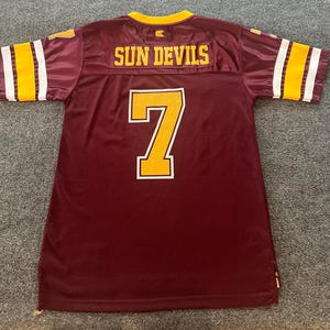 May include: Maroon football jersey with gold and white accents. The number 7 is prominently displayed on the front and back. The words "SUN DEVILS" are across the back. The jersey has gold and white stripes on the sleeves.