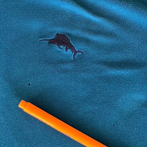 May include: A teal blue fabric with a black embroidered marlin fish design.