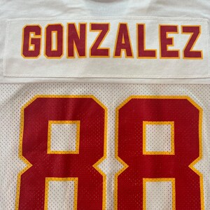 Op de afbeelding: Wit mesh sportshirt met de naam "GONZALEZ" in rode en gouden letters. Het nummer "88" staat in grote rode en gouden cijfers op het onderste deel van het shirt.