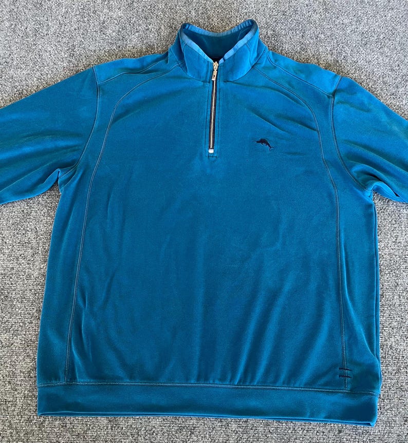 May include: A teal blue quarter zip pullover sweatshirt with a small black marlin logo on the left chest.