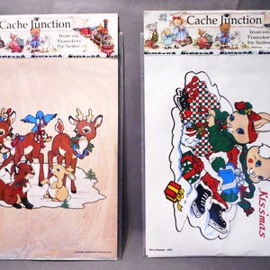 May include: Two iron-on transfer sheets. One features reindeer with Christmas lights and a fox and rabbit. The other has rabbits, ice skates, and the text "Merry Kissmas". Both have the "Cache Junction" logo.