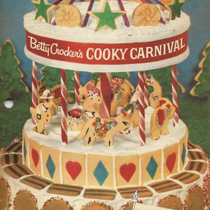 May include: A white cake decorated with a carousel of gingerbread animals and candy canes. The cake is surrounded by a border of brown cookies and topped with a red and white striped canopy. The cake is labeled "Betty Crocker's COOKY CARNIVAL" and "Gold MEDAL" with a picture of a cook book.