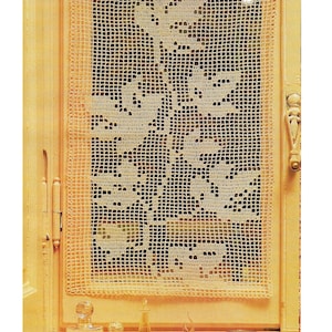 Peut inclure: Un rideau de fenêtre en crochet crème avec un motif floral est suspendu dans un cadre de fenêtre jaune clair. Le rideau est encadré d'une bordure en crochet assortie. Plusieurs flacons de parfum en verre et des roses sont sur le rebord de la fenêtre.