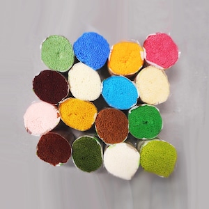May include: A collection of colorful yarn bundles in various shades, including green, blue, yellow, pink, and brown. The yarn is tightly wound and wrapped, creating a textured appearance. The bundles are arranged closely together, showcasing a variety of colors.