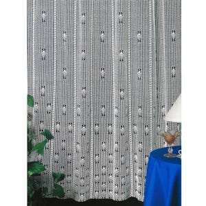 Pode incluir: Cortina branca de tecido aberto com um padrão floral repetido. A cortina é feita de um material delicado e rendado, e pendura em painéis verticais. Uma mesa azul com uma lâmpada e um copo decorativo está no fundo.