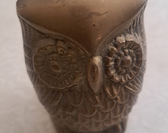 May include: A small, solid brass owl figurine with detailed features, including eyes, beak, and feathers. The owl is a popular decorative item and symbol of wisdom.