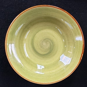 Könnte beinhalten: Eine grüne Keramikschüssel mit braunem Rand und einem wirbelnden Muster. Die Schüssel ist leer und hat eine glänzende Oberfläche.