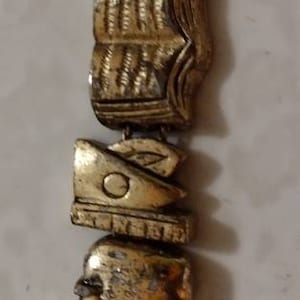 May include: A gold-toned charm bracelet with various charms, including a book, a computer, a pencil, and a house. The charms are connected by a chain and have a detailed design.