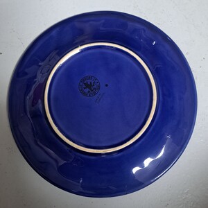 May include: Blue ceramic plate with a white rim and a small black stamp on the bottom that reads "Pinheiro 18, Portugal, Made in Portugal."