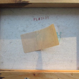 K&ouml;nnte beinhalten: Eine Nahaufnahme der R&uuml;ckseite eines gerahmten Leinwandgem&auml;ldes. Die Leinwand ist wei&szlig; mit einem leichten Blauton und hat einen braunen Papiersticker darauf. Der Rahmen ist aus Holz und braun lackiert. Die Nummer "FL#3425" ist in roter Tinte auf die Leinwand geschrieben.