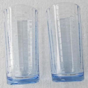 May include: Two clear glass drinking glasses with a light blue tint and a textured design. The glasses have a rounded bottom.