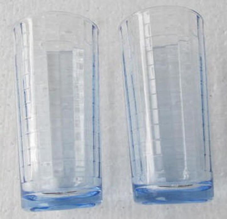 May include: Two clear glass drinking glasses with a light blue tint and a textured design. The glasses have a rounded bottom.