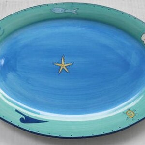 May include: A blue and green oval serving platter with a starfish, a fish, and a seashell design.