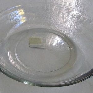 Puede incluir: Un plato para tartas de vidrio transparente con una superficie ligeramente ondulada.