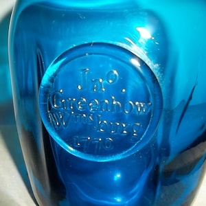May include: A blue glass bottle with a circular embossed label that reads "Jno. Greenhow Wmsburg 1770".