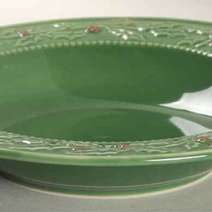 May include: A green ceramic bowl with a raised holly and berry design around the rim. The bowl is perfect for serving holiday snacks or desserts.