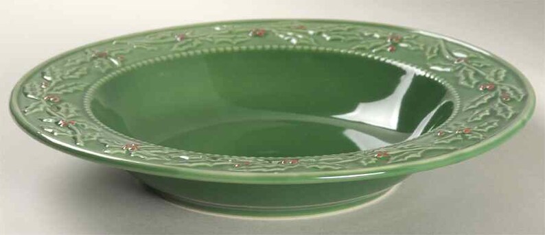 May include: A green ceramic bowl with a raised holly and berry design around the rim. The bowl is perfect for serving holiday snacks or desserts.