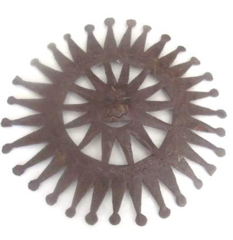 May include: A rusty metal sun with a face and rays, resembling a decorative wall hanging.