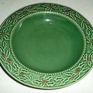 May include: A green ceramic bowl with a raised holly and berry design around the rim.