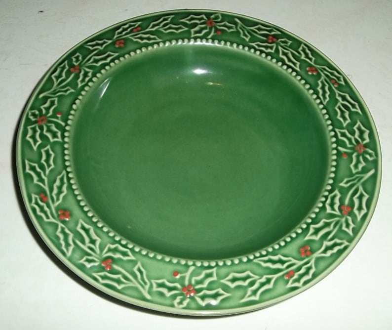 May include: A green ceramic bowl with a raised holly and berry design around the rim.