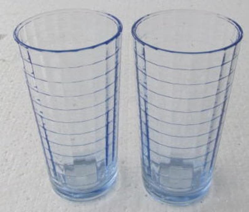 May include: Two tall, clear blue glass drinking glasses with a ribbed pattern. The glasses are empty.