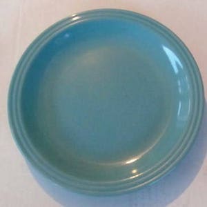 Puede incluir: Un plato de cerámica azul claro con un borde ligeramente elevado.