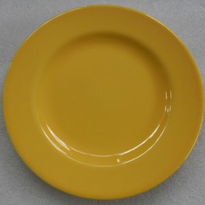 May include: A bright yellow ceramic dinner plate with a slightly raised rim.