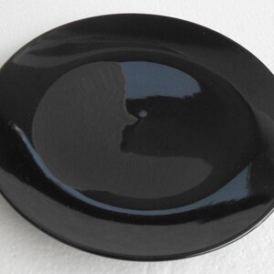 Pode incluir: Um prato de jantar de cerâmica preto com acabamento brilhante.