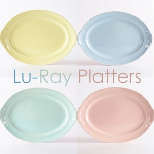 May include: Four oval Lu-Ray platters in different pastel colors: yellow, light blue, light green, and pink. Each platter has two small handles on the sides.