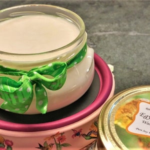 May include: A glass jar of wax melt with a green polka dot ribbon tied around the top. The jar is sitting on a pink and white warming dish. The jar is labelled "Egyptian Amber Warming Melt Jar" with the text "Riley Creek Candle Company" above the label.