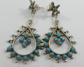 Può includere: Un paio di orecchini pendenti color argento con pietre color turchese. Gli orecchini hanno una forma a goccia con un design a raggiera e piccole pietre turchesi. Gli orecchini sono progettati con chiusura a perno.