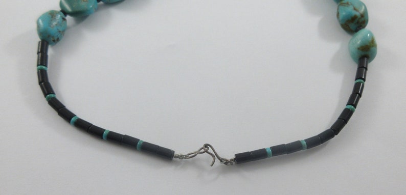 May include: A turquoise and black beaded necklace with a silver clasp.