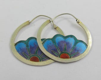 May include: A pair of silver hoop earrings with a floral design. Each earring features a blue and purple flower with a red center and green accents. The earrings are set against a white background.
