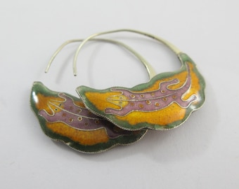 May include: A pair of silver hoop earrings with a green, yellow, and purple enamel design of a lizard.