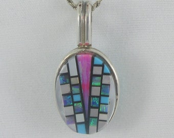 May include: A silver chain necklace with a pendant featuring a geometric design made of turquoise, pink, and white stones.