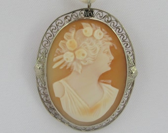 May include: A cameo pendant featuring a woman's profile with a floral crown, set in a silver filigree frame.
