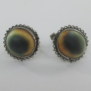May include: A pair of silver earrings with a round, iridescent shell cabochon set in a silver filigree frame.
