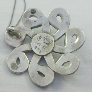 Pu&ograve; includere: Ciondolo in argento a forma di fiore con intricati tagli. Il retro del ciondolo &egrave; timbrato con "925 MESSICO" e "ARIEF PI 207".