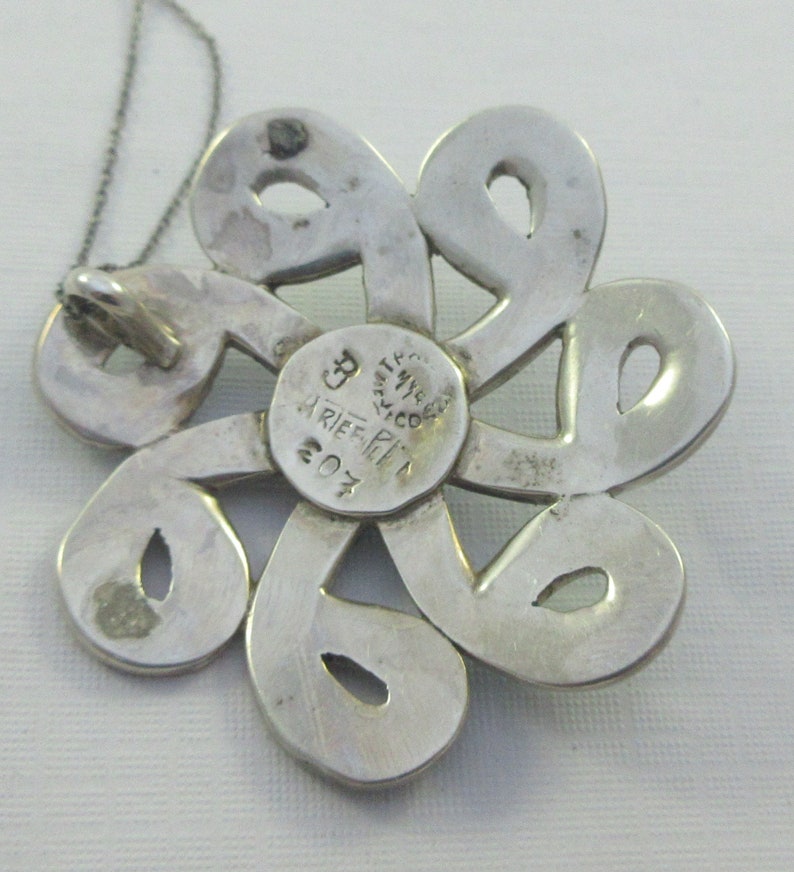 Pu&ograve; includere: Ciondolo in argento a forma di fiore con intricati tagli. Il retro del ciondolo &egrave; timbrato con "925 MESSICO" e "ARIEF PI 207".