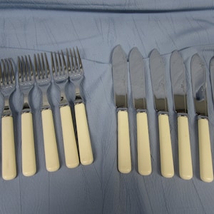 May include: A set of 10 silver-plated cutlery pieces with ivory-coloured handles. The set includes 5 forks and 5 knives.