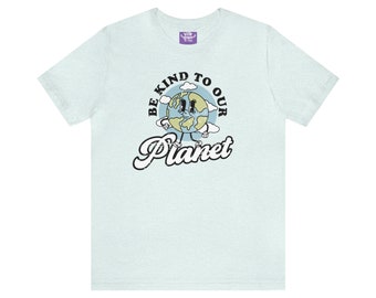 May include: Light blue t-shirt with a graphic of a cartoon Earth with a face and legs. The text "Be Kind To Our Planet" is written in a retro font around the Earth.